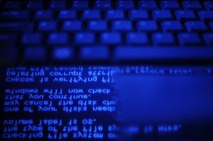 malicious hacking code and keyboard in blue